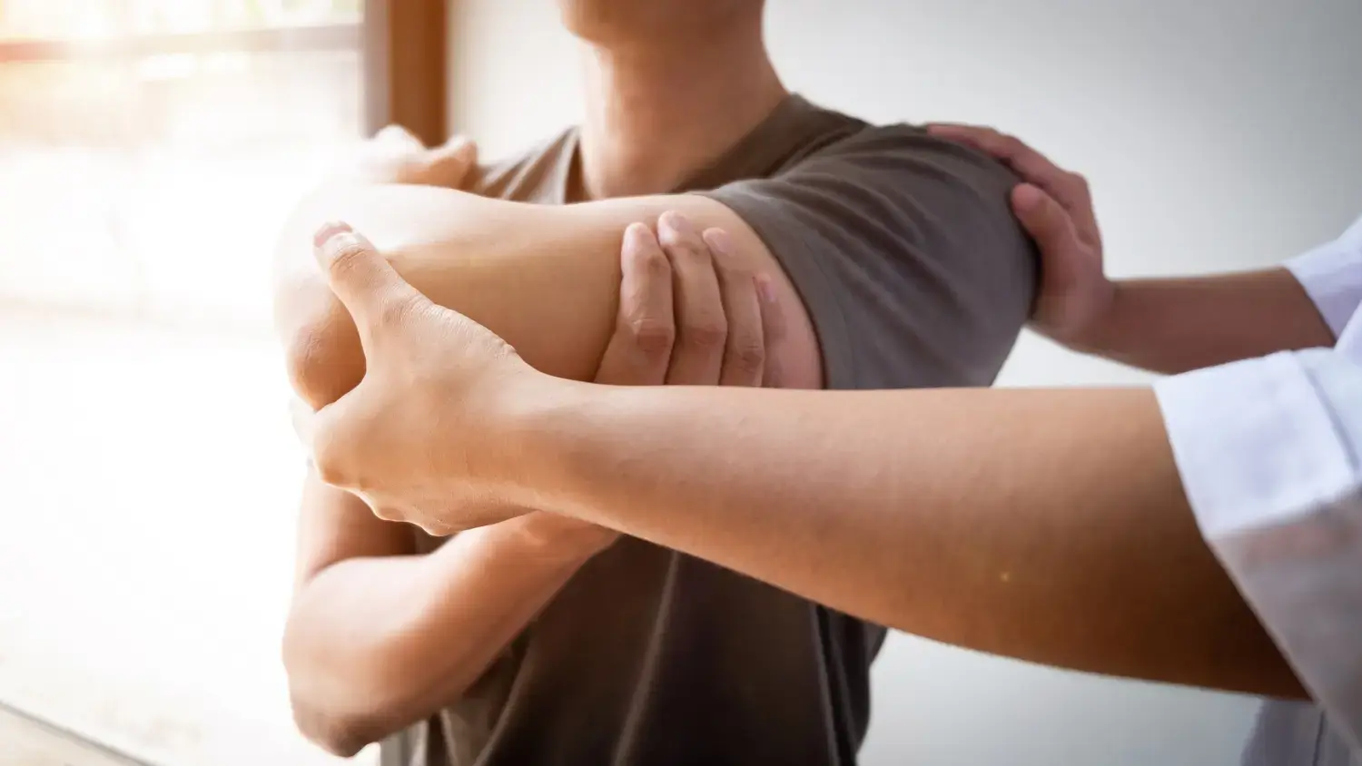 Therapeut, der einen verletzten Mann mit der Rotatorenmanschetten-Dehnungsmethode behandelt.